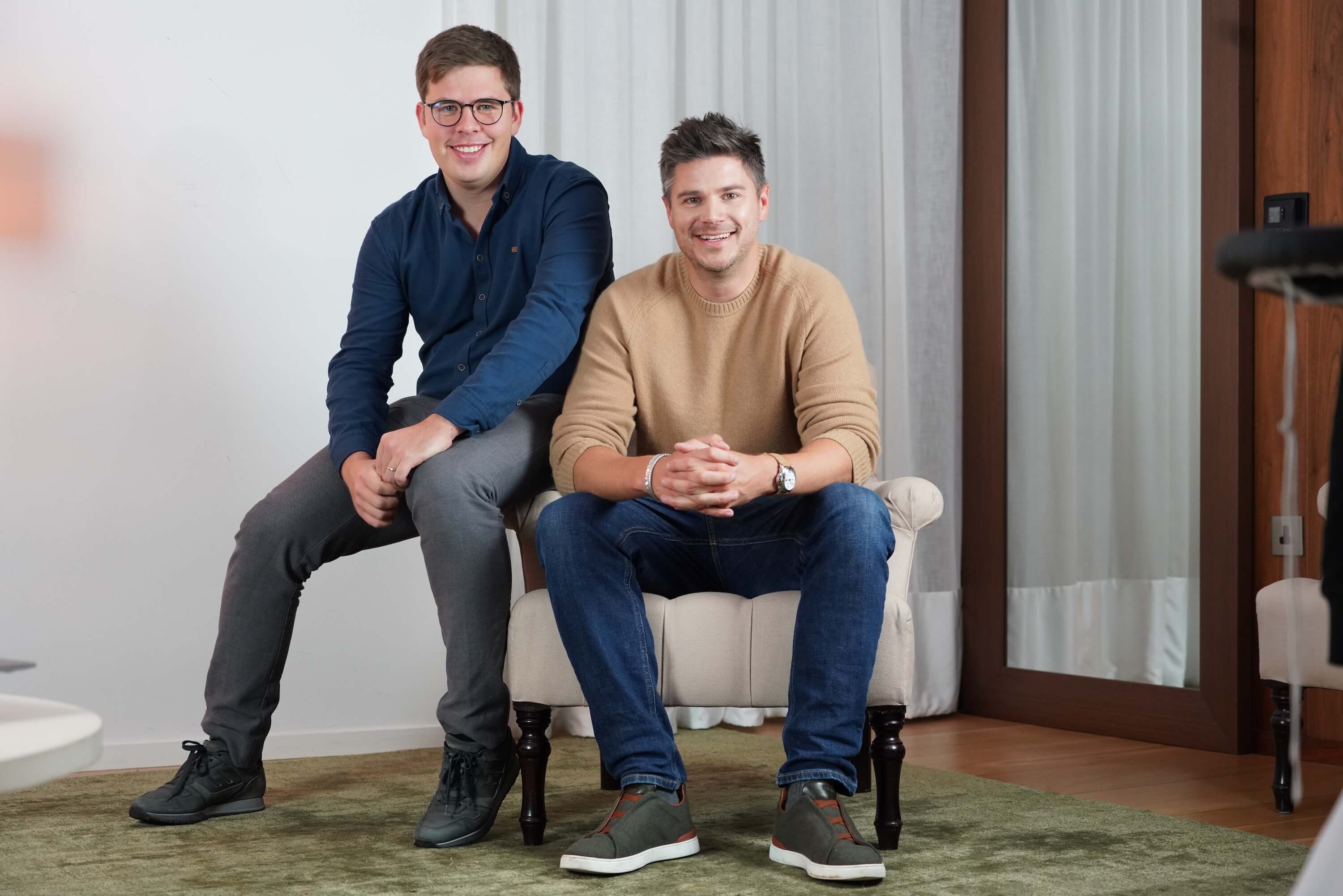 A picture of the current sequel team showing Alex Macdonald and Philipp Omenitsch, seated on a sofa together. Alex is seated on the chair itself, and Philipp is seated on the armrest to his left.